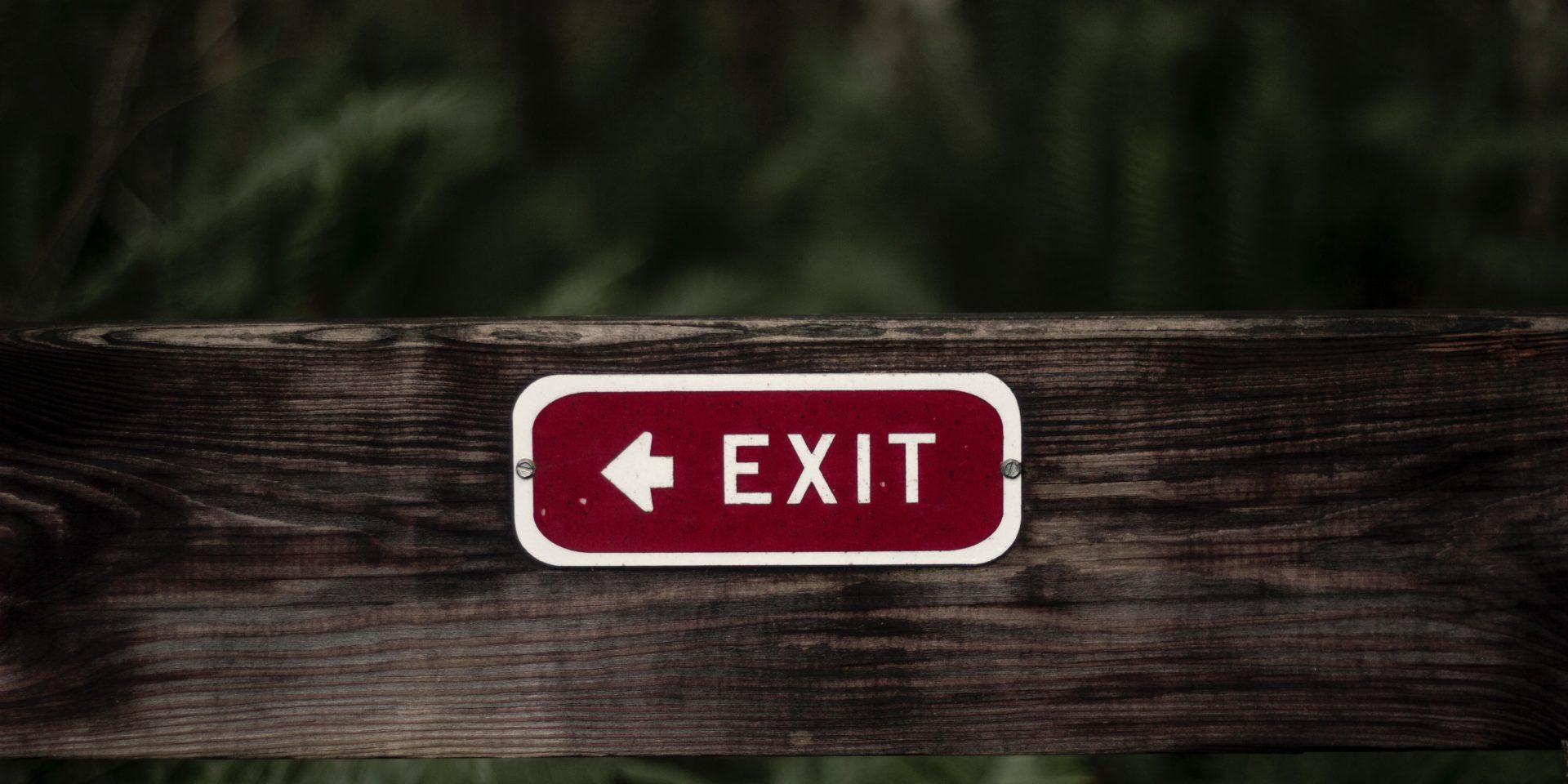 Employee retention rate – red exit sign on a wooden fence showing challenges in attracting and retaining employees