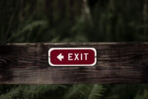 Employee retention rate – red exit sign on a wooden fence showing challenges in attracting and retaining employees