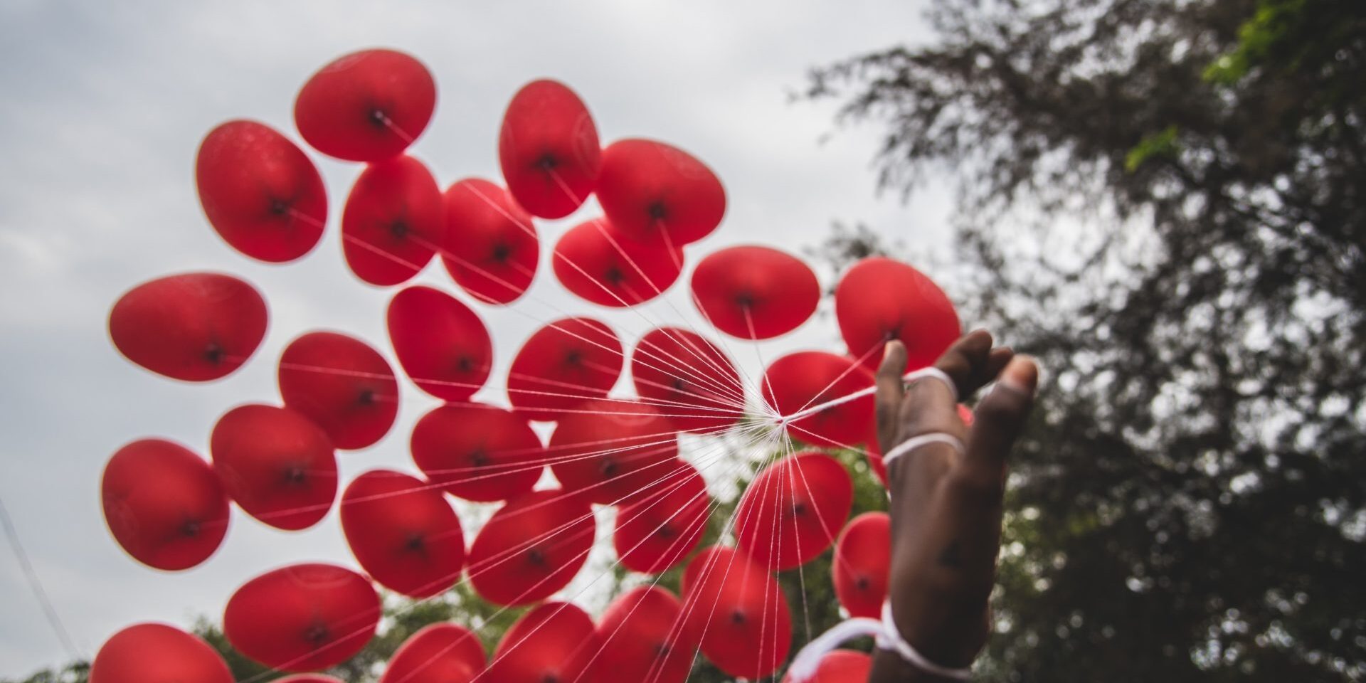 Hand holding red balloons - Birmingham Children's Hospital Charity partnership announcement
