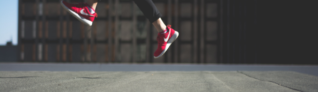 How to raise your professional profile - person in red shoes jumping in front of a block of flats