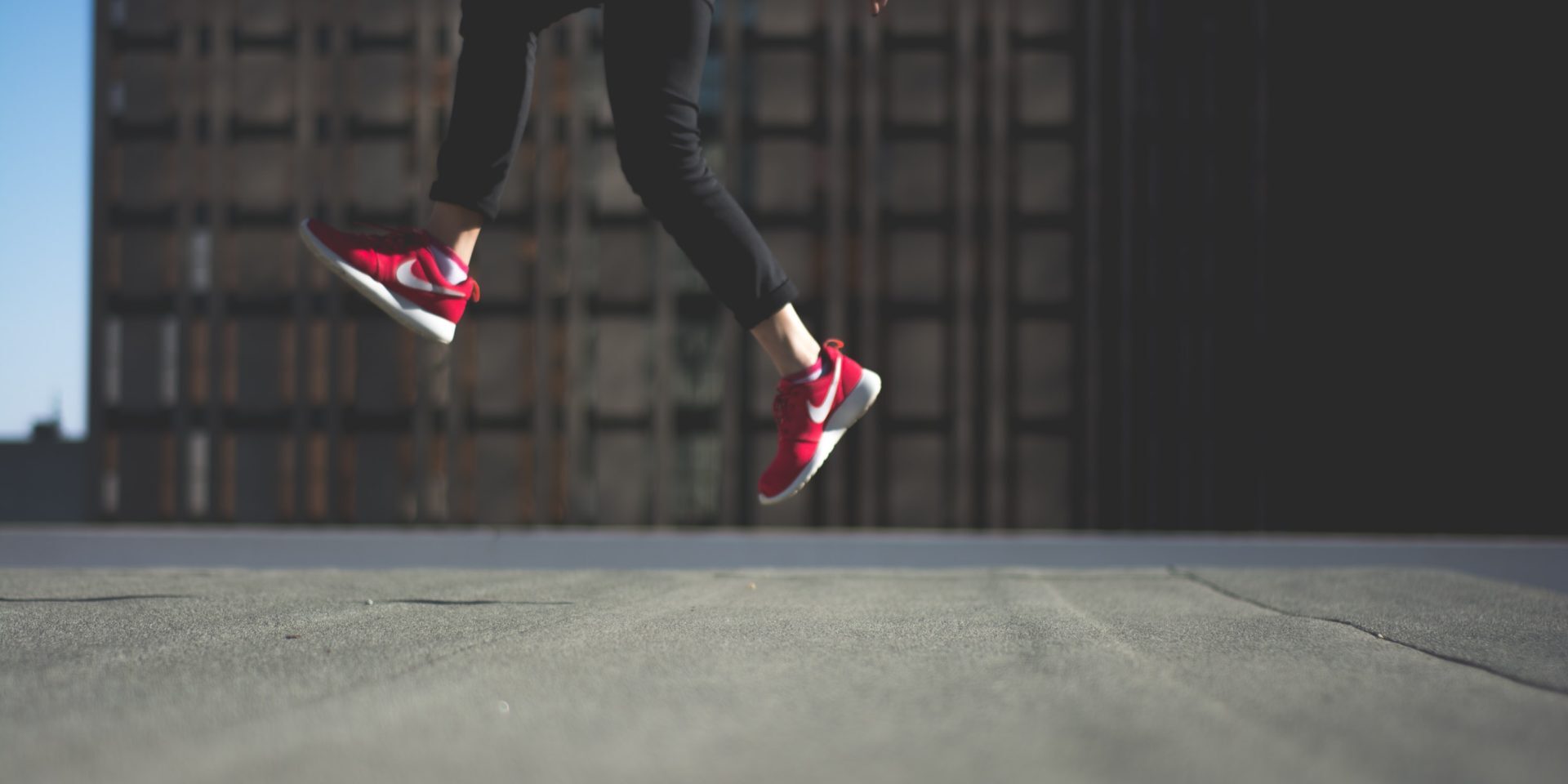 How to raise your profile at work: person wearing red Nike trainers jumping in front of a building