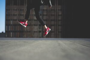 How to raise your profile at work: person wearing red Nike trainers jumping in front of a building