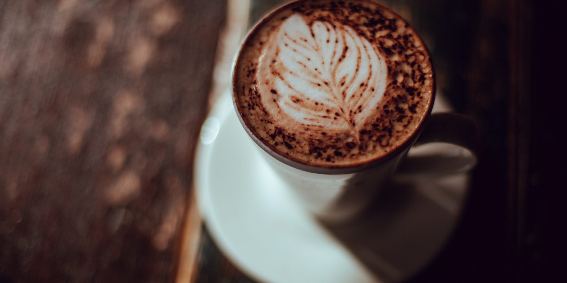 coffee in white mug with latte art against dark wooden background – JDE recruitment case study